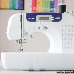 Pictured Brother CS6000i sewing machine. Rainbow quilts blurred in background on the wall.