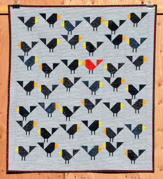 pictured quilt with black birds hanging on a wooden backdrop