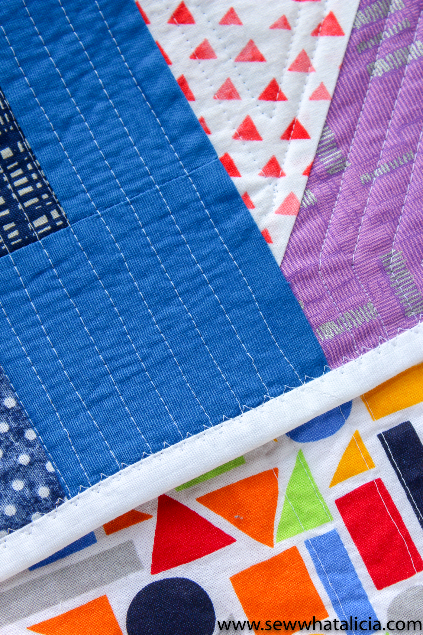 Scrappy Easy Rainbow Quilt Pattern and Tutorial: Pictured edge of quilt with white binding evident. | www.sewwhatalicia.com
