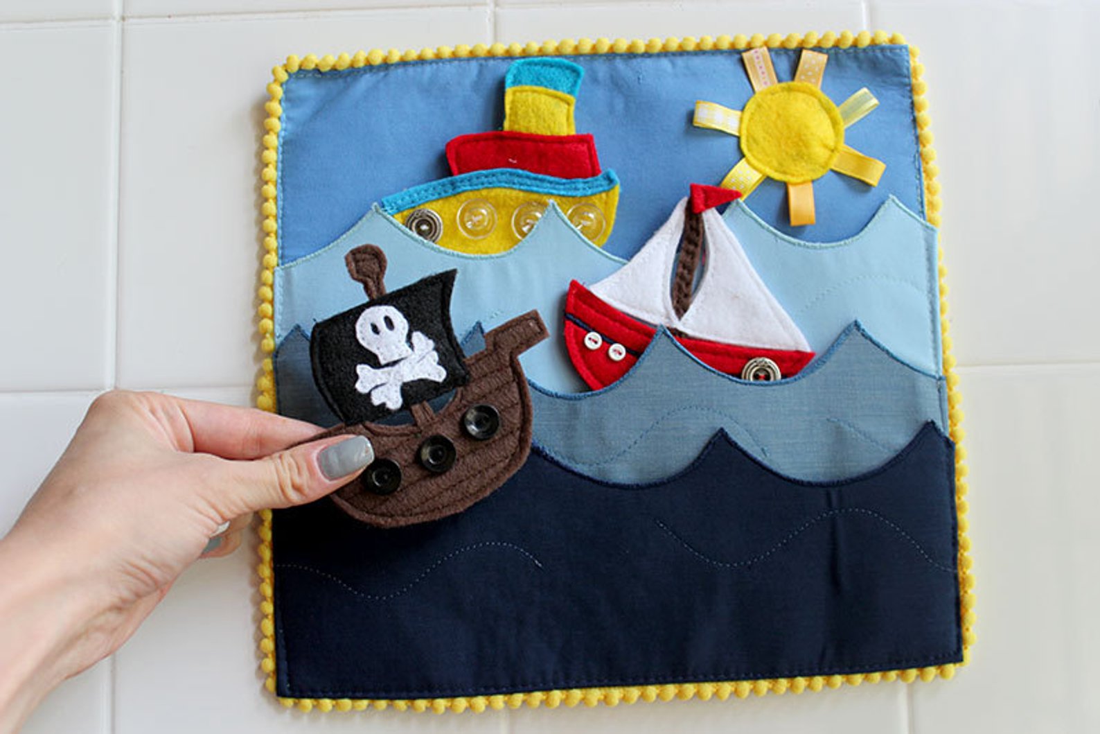 Fabric quiet book open to a page with button-flap activities for toddlers