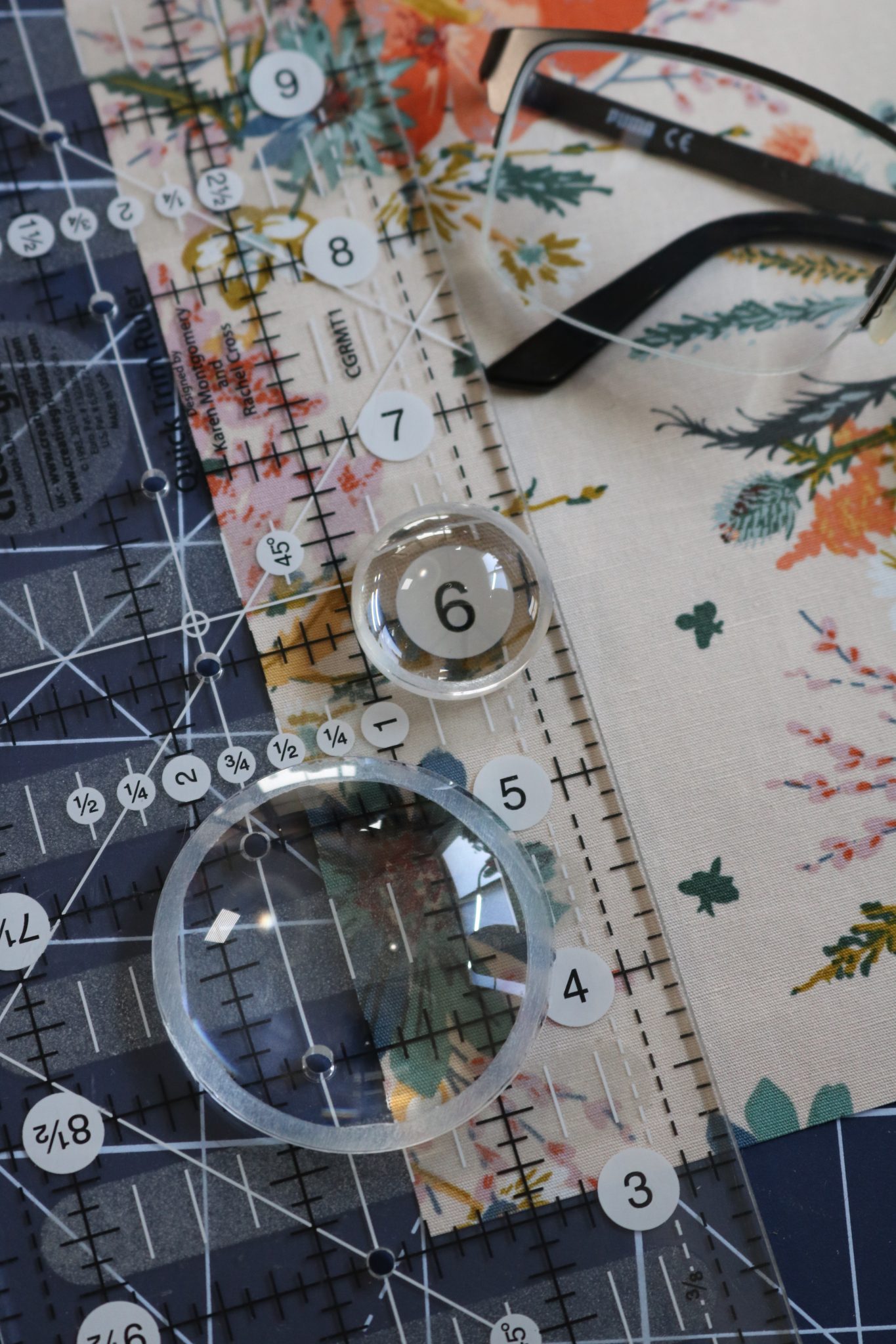 fabric with ruler on top with magnifying dots on top and glasses in background